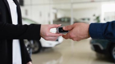 Kadın araba yöneticisi, bayilikte müşteriye anahtar veriyor. Satıcı ve müşteri anlaşma yapmak için el sıkışıyor. Eller kapalı, arka plan bulanık. Araba satışı kavramı