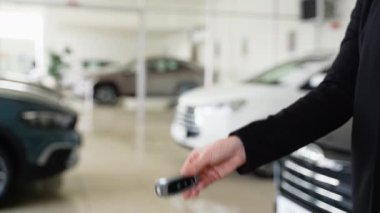 Kadın araba yöneticisi, bayilikte müşteriye anahtar veriyor. Satıcı ve müşteri anlaşma yapmak için el sıkışıyor. Eller kapalı, arka plan bulanık. Araba satışı kavramı