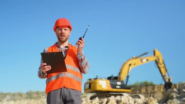 Foreman, maden ocağında telsiz kullanarak sondaj makinesinde çalışanlara emir veriyor. Endüstriyel işçi mühendisi taş ocağında telsiz telsizi kullanıyor.