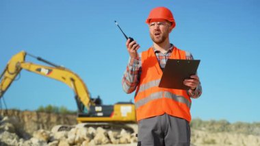 Foreman, maden ocağında telsiz kullanarak sondaj makinesinde çalışanlara emir veriyor. Endüstriyel işçi mühendisi taş ocağında telsiz telsizi kullanıyor.