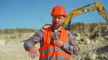 Foreman, maden ocağında telsiz kullanarak sondaj makinesinde çalışanlara emir veriyor. Endüstriyel işçi mühendisi taş ocağında telsiz telsizi kullanıyor.
