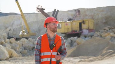 Maden ocağı işçisi, güvenlik önlüğü ve inşaat alanı boyunca yürür. Kum taşı madenciliği uzmanı. Açık maden endüstrisi kavramı