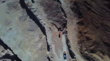 Sarı kazıcı inşaat alanındaki bir çöp kamyonuna toprak yüklüyor. Kazıcı bir çöp kamyonuna toprak yüklüyor. Kazıcı inşaat alanının zeminini kazıyor. Toprağın kaldırılması