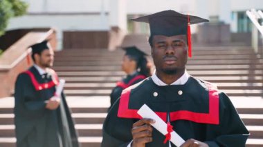 Genç Afrikalı Amerikalı öğrenci üniversite kampüsünde çok ırklı bir grup arkadaşla duruyor. Eğitim, mezuniyet ve halk konsepti - bir grup uluslararası öğrenci