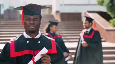 Üniversite kampüsündeki mezuniyet gününde çok ırklı bir arkadaş grubuyla birlikte Afrika kökenli Amerikalı bir öğrenci. Eğitim, mezuniyet ve halk konsepti - bir grup uluslararası öğrenci manto içinde