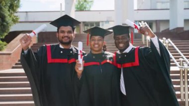 Mezuniyetlerini kutlamak için üniversite kampüsünde kucaklaşan Afro-Amerikan öğrenci grubu. Eğitim, mezuniyet ve halk konsepti - bir grup uluslararası öğrenci