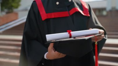 Elinde kırmızı püskül ve diploması olan siyah şapkalı bir mezun. Eğitim, mezuniyet ve halk konsepti - Manto ve şapka giymiş Hintli Asyalı öğrenci