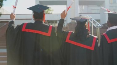 Üniversite kampüsünde diplomalı, mezuniyet elbisesi giyen üç üniversite mezunu. Eğitim, mezuniyet ve halk konsepti - dış etek ve kep giymiş bir grup uluslararası öğrenci
