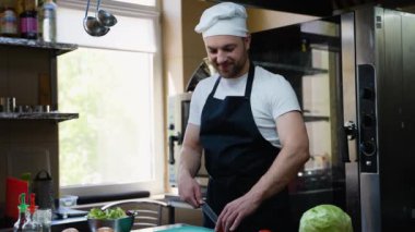 Şef mutfakta taze vejetaryen salatası hazırlıyor. Yakışıklı adam lezzetli yemekler hazırlıyor. Yemek pişirme, sağlıklı yemek, meslek ve insan konsepti.