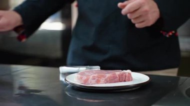 Adam bifteğe tuz serpiyor. Restoran mutfağında profesyonel aşçı. Şef biftek pişiriyor.