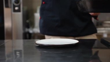 Şef pişmiş bifteği bir restoranın mutfağında bir tabağa koyar. Lokanta mutfağında profesyonel aşçı.