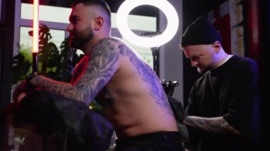 Dövme sanatçısı, kuaförde müşterisinin sırtına dövme yaptırır. Sırtındaki dövme. Sanat konsepti