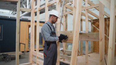 Prefabrik inşaat alanında çalışan yakışıklı bir inşaatçı. Fabrikadaki modern modüler ev yapımı.