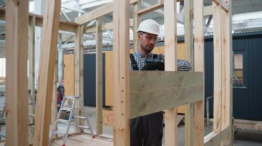 Fabrikadaki modern modüler evin yapımı. Matkap kullanan ve prefabrik konutların geliştirilmesi üzerinde çalışan işçiler