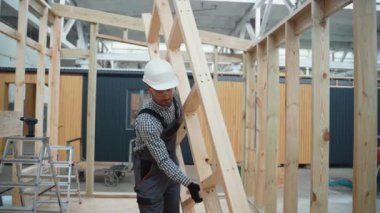 Üniformalı marangoz mühendisi inşaat alanındaki tamamlanmamış modüler evlerin içinden geçiyor. Fabrikadaki modern modüler evin yapımı. Ekolojik kavram
