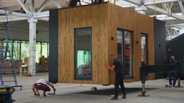 İşçiler prefabrik modüler bir evi kamyona yüklüyorlar. Modüler ev nakil için hazır. Taşınabilir ahşap evin gönderimi ve taşınması işlemi