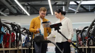 Teknoloji mağazasından yeni elektrikli süpürge alan genç bir çift. Yeni teknoloji konsepti. Alışveriş zamanı eğleniyor. Ev aletleri mağazasında genç bir çift.