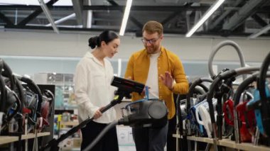 Yeni ev için elektrikli süpürge dükkanından elektrikli süpürge seçen çift. Yeni teknoloji konsepti. Alışveriş zamanı eğleniyor. Ev aletleri mağazasında genç bir çift.