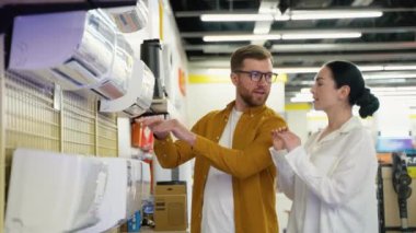 Bir çift yeni ev aletleri mağazasında klima seçiyor. Evli bir çift, ev aletlerini hipermarketten seçer. Büyük indirim, Kara Cuma.