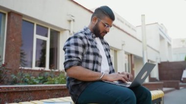 Hintli öğrenci üniversite kampüsünde okumak için dizüstü bilgisayar kullanıyor. Eğitim kavramı, gençlik, bilgi
