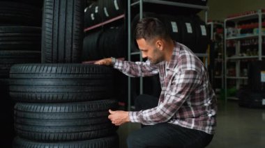 Erkek bir müşteri süpermarkette yeni lastikler seçiyor. Mevsim için lastik seçme kavramı