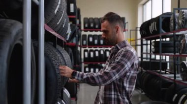 Bir adam lastik dükkanında yeni bir lastik seçer. Mevsim için lastik seçme kavramı