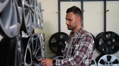 Mağazadan yeni bir alaşımlı araba tekerleği alan bir adam. Otomotiv işi, otomobil parçaları satışı