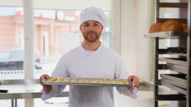 Fırıncı metal bir tepside çiğ kek pişiriyor. Yemek pişirme süreci. Fırın yapımı taze pişmiş yiyecekler. Pastane kavramı. Baker fırında ekmek yapıyor.