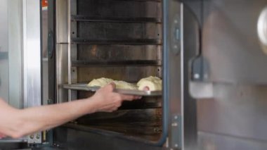 Baker çörekleri ve kruvasanları profesyonel fırına koyar. Fırın yapımı taze pişmiş yiyecekler. Baker pastanede kruvasan yapıyor.