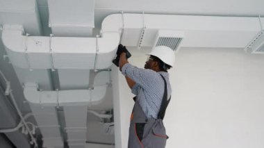 Afrika kökenli Amerikalı işçiler havalandırma ve havalandırma için boru sistemi kuruyor. HVC teknisyeni iş başında. Havalandırma, ısıtma sistemi bakım ve onarım