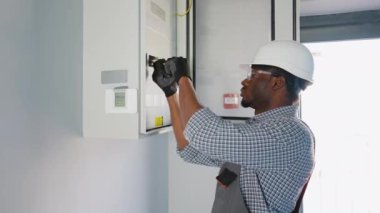 Afrikalı Amerikalı elektrikçi. Ofiste kontrol, onarım, bakım ve elektrik sistemi var..