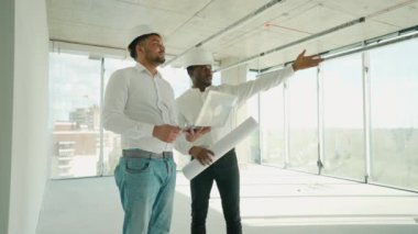 Hintli mimar ve Afrikalı yönetici inşaat alanında buluşuyorlar. Çok ırklı işçi ve mühendis plan üzerinde tartışıyorlar. Yeni bir binayı ziyaret ederken birlikte çalışan iki inşaat işçisi.