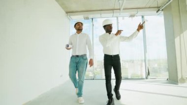 Hintli mimar ve Afrikalı yönetici inşaat alanında buluşuyorlar. Çok ırklı işçi ve mühendis plan üzerinde tartışıyorlar. Yeni bir binayı ziyaret ederken birlikte çalışan iki inşaat işçisi.