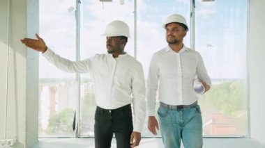 Hintli mimar ve Afrikalı yönetici inşaat alanında buluşuyorlar. Çok ırklı işçi ve mühendis plan üzerinde tartışıyorlar. Yeni bir binayı ziyaret ederken birlikte çalışan iki inşaat işçisi.