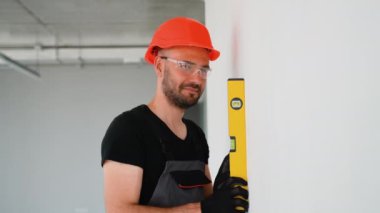 Ruh seviyesi ölçüm duvarı olan profesyonel bir inşaatçı. Onarım, inşaat, teknoloji ve ev konsepti