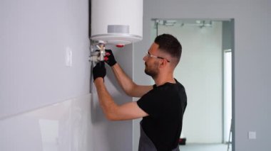 Mühendis eve bir doğal gaz kazanı kuruyor ve boruları kontrol ediyor. Isıtma servisi bakım konsepti. Gaz kazanının tamiri