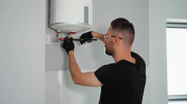 Mühendis eve bir doğal gaz kazanı kuruyor ve boruları kontrol ediyor. Isıtma servisi bakım konsepti. Gaz kazanının tamiri