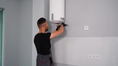Mühendis eve bir doğal gaz kazanı kuruyor ve boruları kontrol ediyor. Isıtma servisi bakım konsepti. Gaz kazanının tamiri