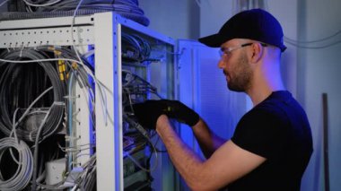 Uzmanlık alanı, sunucu odasındaki internet cihazları ve kablolar üzerinde çalışıyor. Bilgi işlem mühendisi sunucu odasında internet ağı kuruyor