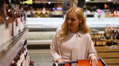 Bir kadın perakende mağazasından bir şişe şarap seçiyor.