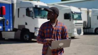 Laptoplu Afro-Amerikan kamyon şoförü kamyon parkında takılıp düşmeye hazırlanıyor. Nakliye ve ulaşım kavramı. Kamyoncu yaşam tarzı