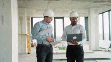 Hintli ve beyaz dizüstü bilgisayarlı tasarımcılar yeni bir ofis yenilemesi yapmayı planlıyorlar..