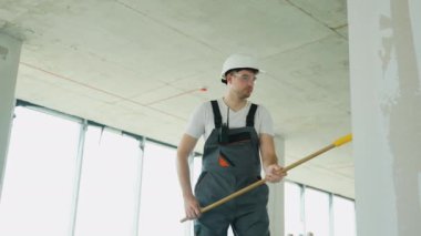 Bir tadilat projesi sırasında duvar kaplamasını silindirle uygulayan bir müteahhit görülüyor. Güvenlik teçhizatı var.