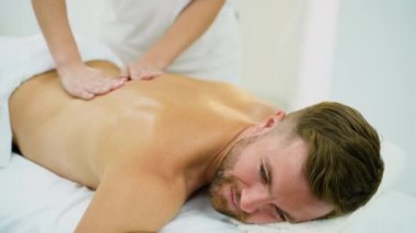 Erkek bir müşterinin spa 'da rahatlatıcı bir sırt masajı yaptırdığı yakın plan bir fotoğraf. Masaj terapisti gerginliği azaltmak ve derin rahatlama ve gençleşmeyi teşvik etmek için nazik teknikler kullanır.