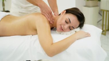 Yetenekli bir masöz rahatlatıcı bir kaplıcada bir kadına boyun masajı sağlar. Bu terapi seansı gerilimi azaltmaya, dolaşımı iyileştirmeye ve genel rahatlama ve refahı arttırmaya yardımcı olur.
