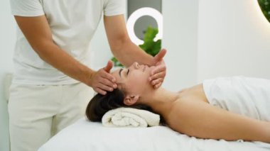 Bir terapist, sakin bir spa ortamındaki bir kadına rahatlatıcı bir kafa masajı sağlar. Oturum stresin azalmasına, rahatlamanın teşvik edilmesine ve genel olarak rahatlatıcı bir ortamda refahın artmasına yardımcı olur.