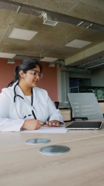 Hintli doktor dizüstü bilgisayar kullanarak online danışmanlık yapıyor. Bu resim, tıbbi alandaki teletıp ve dijital iletişim odaklı modern sağlık uygulamalarını temsil etmektedir.