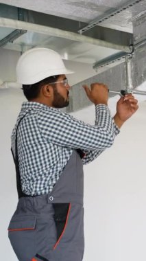 Hintli teknisyen bir ofis binasına havalandırma sistemi kuruyor. Bu fotoğraf, uygun hava dolaşımı ve güvenliği için havalandırma sistemi kurulumu ve bakımı kavramını temsil etmektedir.