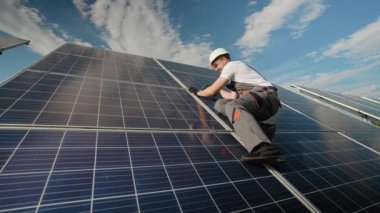 Yetenekli bir teknisyen enerji verimliliğini arttırmak için bir güneş panelinin güvenli bir şekilde kurulmasını sağlar. Görüntü, güneş enerjisi sistemleri ve temiz enerji girişimlerinin ardındaki dikkatli çalışmayı gösteriyor