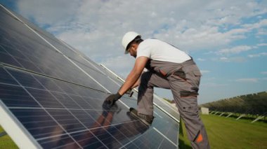 Koruyucu giysili Hintli işçiler güneş panellerinde bir güneş çiftliğinde bakım yapıyorlar. Çalışmaları sürdürülebilir bir enerji geleceği için bu yenilenebilir enerji sistemlerinin optimal performansını güvence altına alıyor